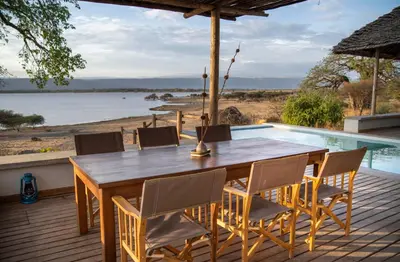 a wooden table and chairs on a deck with a pool at Manyara's Secret in Mto wa Mbu