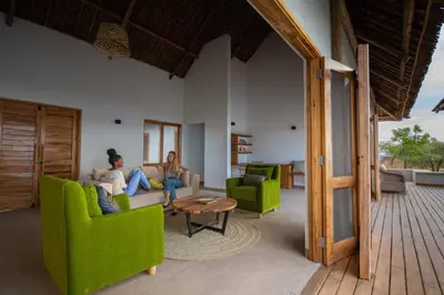 two people sitting in a living room with green chairs at Manyara's Secret in Mto wa Mbu