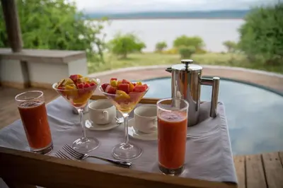 a table with glasses of juice and a bowl of fruit at Manyara's Secret in Mto wa Mbu