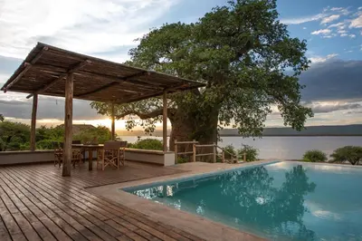 a pool with a table and a pavilion next to the water at Manyara's Secret in Mto wa Mbu