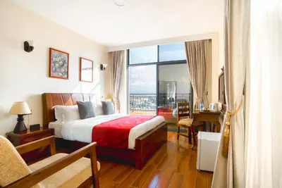 a hotel room with a bed and a large window at Kibo Palace Hotel Moshi in Moshi