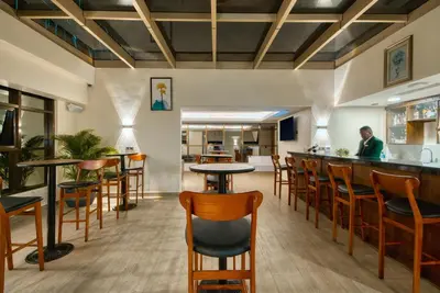 a bar in a restaurant with wooden tables and chairs at Kibo Palace Hotel Moshi in Moshi