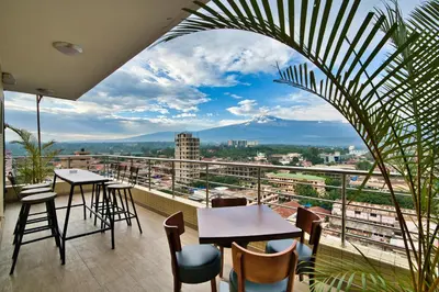 a balcony with tables and chairs and a view of a city at Kibo Palace Hotel Moshi in Moshi