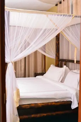 a bedroom with a canopy bed with white drapes at Burka Coffee Lounge in Arusha