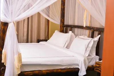 a bedroom with a canopy bed with white sheets and pillows at Burka Coffee Lounge in Arusha