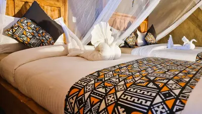 two beds in a room with white towels at Africa Safari Maasai Boma in Serengeti