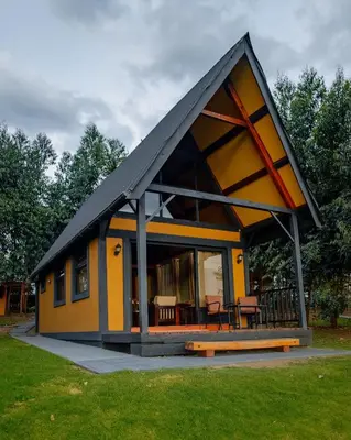 a small yellow house with a black roof at Shamba Lodge Cabin C in Olmotoni