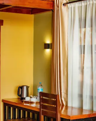 a wooden table with a wooden chair and a curtain at Shamba Lodge Cabin C in Olmotoni