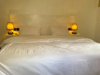 a large white bed with two lamps on either side of it at Home Villa Eco Boutique in Arusha