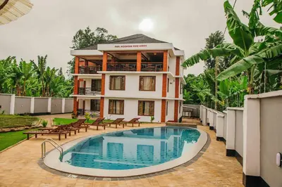 a villa with a swimming pool in front of a house at Dual Mountain View Lodge in Moshi