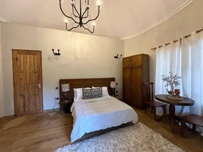 a bedroom with a bed and a table and a chandelier at Tulivu Kilimanjaro Retreat in Msaranga