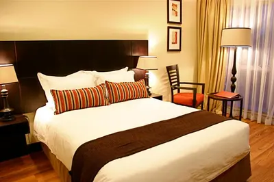 a hotel room with a large bed and a chair at Mount Meru Hotel in Arusha