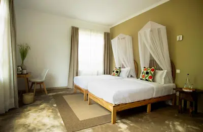 a bedroom with two beds and a large window at The Safari House in Usa River
