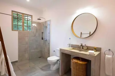a bathroom with a toilet and a sink and a mirror at The Safari House in Usa River