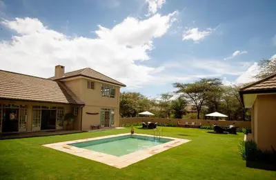 a yard with a swimming pool and a house at The Safari House in Usa River