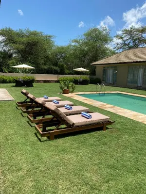 a group of lounge chairs next to a swimming pool at The Safari House in Usa River