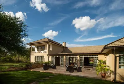 a house with a patio with chairs in the yard at The Safari House in Usa River