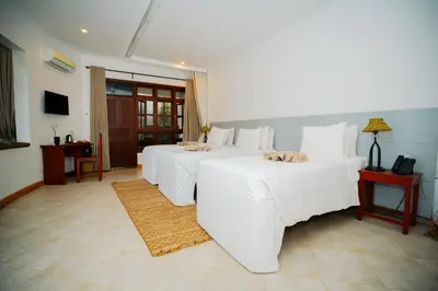 a bedroom with three beds with white sheets at Arusha Planet Lodge in Arusha