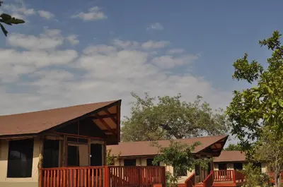 a house with a wooden porch and a roof at Elephant Rock Luxury Camp Tarangire in Kaiti