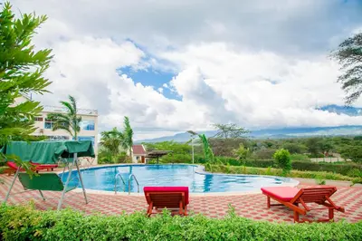 a swimming pool with two chairs and a table at A1 Hotel and Resort in Arusha