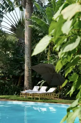 two lounge chairs with an umbrella next to a pool at Tulia Retreat Hotel and Spa in Arusha