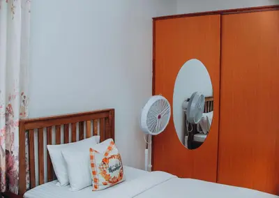 a bedroom with a bed with a mirror and a fan at Royal Homestay in Arusha