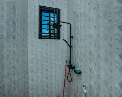 a shower in a bathroom with a window at Royal Homestay in Arusha