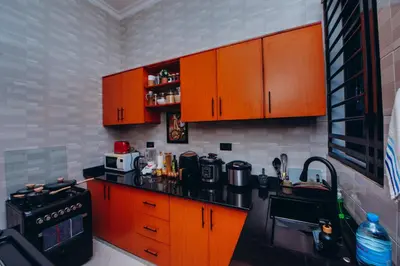 a kitchen with orange cabinets and a black counter top at Royal Homestay in Arusha