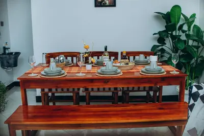 a wooden table with plates and wine glasses on it at Royal Homestay in Arusha