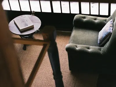 a living room with a table and a chair and a book at Meru House Lekisilai in Arusha