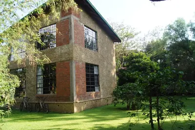 a brick building with windows on a green lawn at Meru House Lekisilai in Arusha