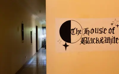 a hallway with a wall with a house of blackmagic sign at The House of Black and White in Arusha