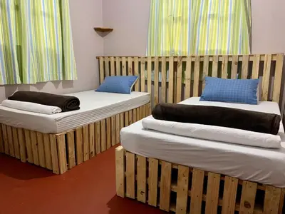 two wooden beds with pillows on them in a room at Pazuri Hostel in Moshi