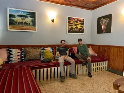 two men sitting on a couch in a room at Pazuri Hostel in Moshi