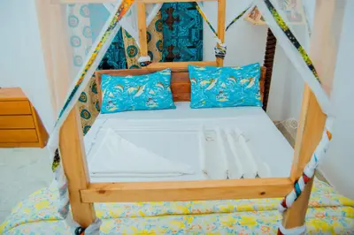 a bed in a tent with blue pillows at The Belle View Inn Bed & Breakfast in Moshi