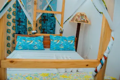 a bedroom with a bed with blue pillows at The Belle View Inn Bed & Breakfast in Moshi
