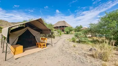 a tent with a chair in the middle of a field at Africa Safari Lake Natron Camping in Mtowabaga