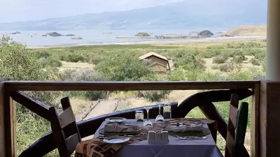a table with a view of the desert from a balcony at Africa Safari Lake Natron Camping in Mtowabaga