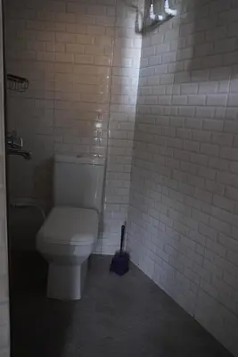 a bathroom with a toilet in a white tiled wall at New Dream House in Arusha