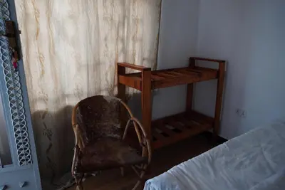 a bedroom with a chair next to a bed and a shelf at New Dream House in Arusha