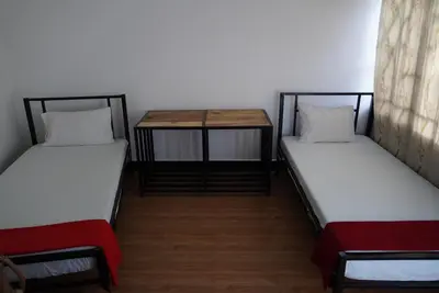 two beds sitting in a room with a table at New Dream House in Arusha