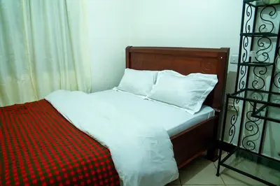 a bed with white sheets and pillows in a room at New Dream House in Arusha