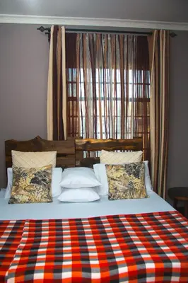 a bed with a red and blue plaid blanket at MINA CHAI HOUSE BNB in Arusha