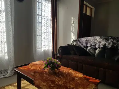 a living room with a leather couch and a table at MINA CHAI HOUSE BNB in Arusha