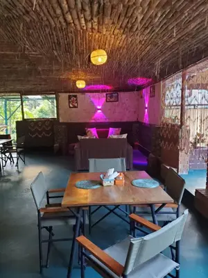 a dining room with tables and chairs and purple lights at Kizumba House in Arusha