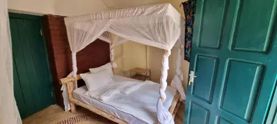 a bed with a canopy in a room with a door at Kizumba House in Arusha