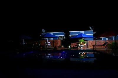 a building with blue umbrellas and a pool at night at Johnsons Villas in Zame