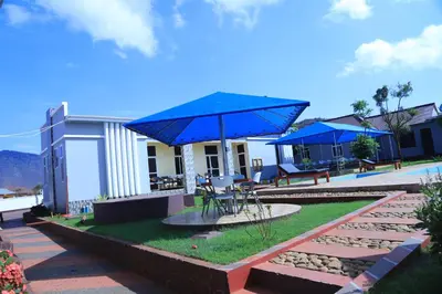 a patio with a blue umbrella in front of a building at Johnsons Villas in Zame