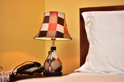 a lamp on a table next to a bed with a phone at Johnsons Villas in Zame