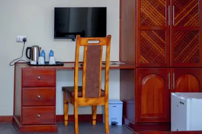 a wooden chair sitting next to a desk with a television at seven skies hotel in Arusha